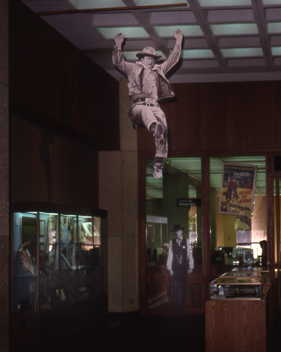 Life-sized John Wayne cut-out leaps into the center of my “Western Film” exhibit, UT Austin, 1991.